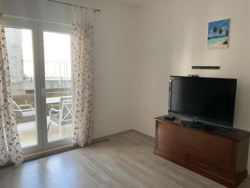 a living room with a flat screen tv next to a window at Apartments Epidaurus in Cavtat