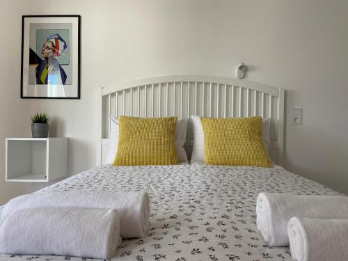 a white bedroom with a large bed with yellow pillows at Astos Vila in Palanga