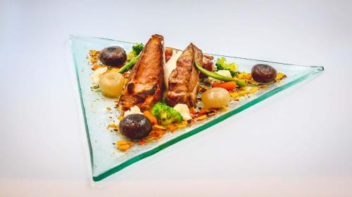 a plate of food with fish and vegetables on it at El Cortijo de Zahara by QHotels in Zahara de los Atunes