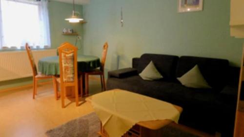 a living room with a black couch and a table at Ferienwohnung - Zimmervermietung Ringelmann in Dettelbach