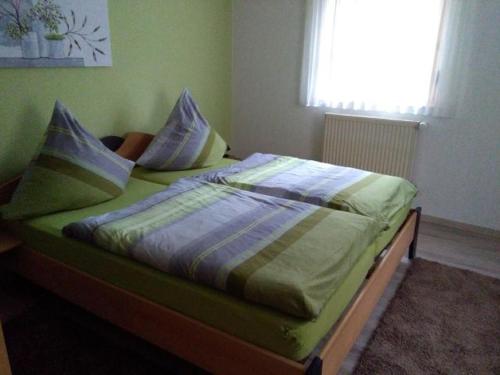 1 dormitorio con cama con sábanas y almohadas verdes en Ferienwohnung - Zimmervermietung Ringelmann, en Dettelbach