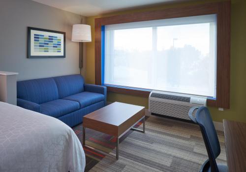 a hotel room with a bed and a couch and a window at Holiday Inn Express Doral Miami by IHG in Doral