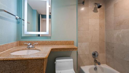 a bathroom with a sink and a toilet and a mirror at Best Western Plus Oceanside Inn in Fort Lauderdale