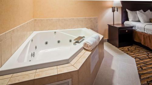 Best Western Danville Inn في دانفيل: حوض استحمام كبير في غرفة الفندق مع سرير