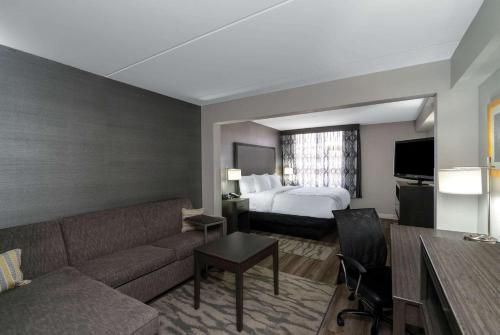 a hotel room with a couch and a bed at La Quinta by Wyndham Raleigh Downtown North in Raleigh