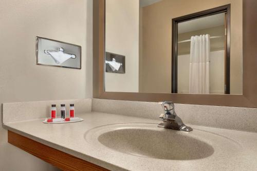 a bathroom with a sink and a mirror at Super 8 by Wyndham Sioux Falls in Sioux Falls