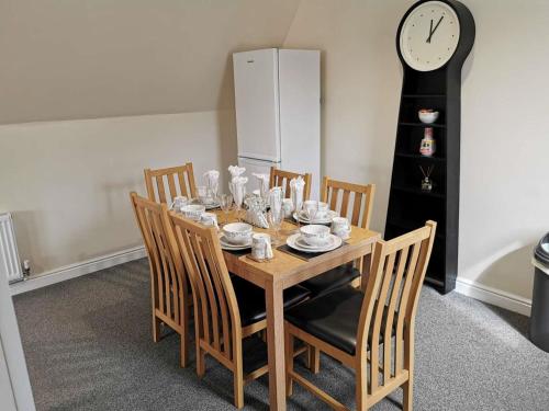 a dining room table with chairs and a clock at Balmaha Lodges and Apartments in Balmaha