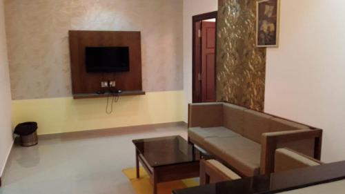a living room with a couch and a tv at Vamoose Mudra Midtown in Kalasa