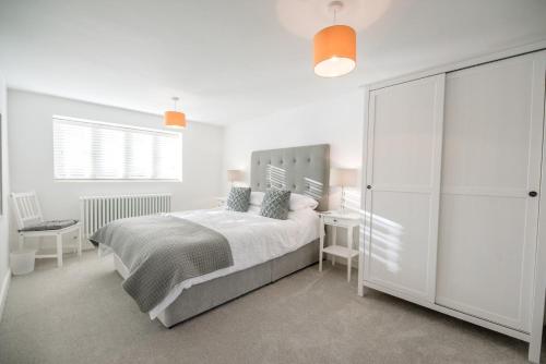 a white bedroom with a bed and a white cabinet at The Old Foundry Long Melford Air Manage Suffolk in Sudbury