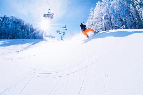 a person skiing down a snow covered slope with a ski lift at Pohorje Village Wellbeing Resort - Family Apartments Bolfenk in Pohorje