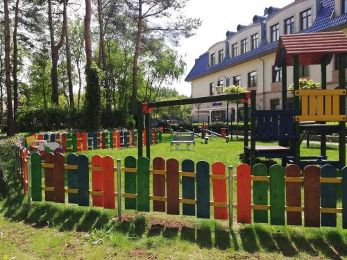 a playground in a park with a colorful fence at Hotel Park Kajetany in Nadarzyn