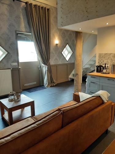ein Wohnzimmer mit einem braunen Sofa und einer Küche in der Unterkunft Appartementen Hoek 1 in Baflo