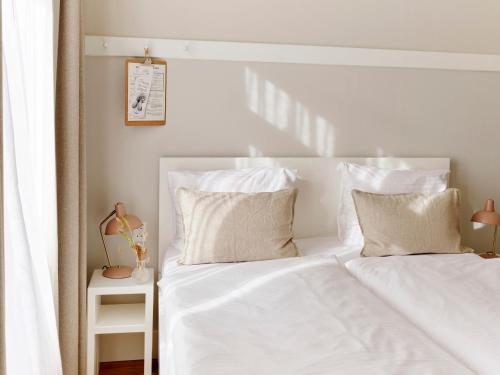 - un lit blanc avec des draps et des oreillers blancs dans l'établissement Hotel Zonne, à Noordwijk aan Zee