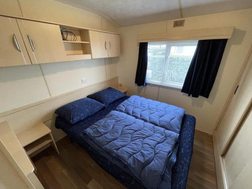 a small bedroom with a blue bed in a caravan at Beach Resort Nieuwvliet Bad - 274 in Nieuwvliet