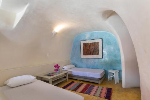 a bedroom with two beds and a blue wall at Caveland in Karterados