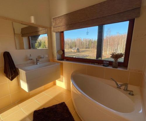 ein Bad mit einer Badewanne, einem Waschbecken und einem Fenster in der Unterkunft Sunset Beach House in Tūja