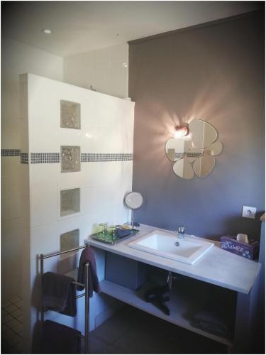 La salle de bains est pourvue d'un lavabo et d'une lumière sur le mur. dans l'établissement Les Ricochets - Maison d'hôtes, à Saint-Denis-lès-Martel