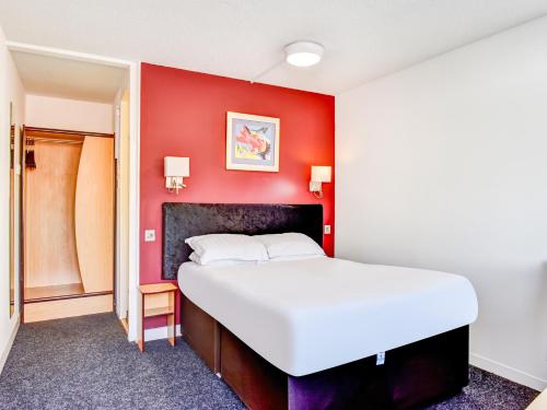 a bedroom with a white bed and a red wall at OYO The Hotel Rafiya, Redditch in Redditch