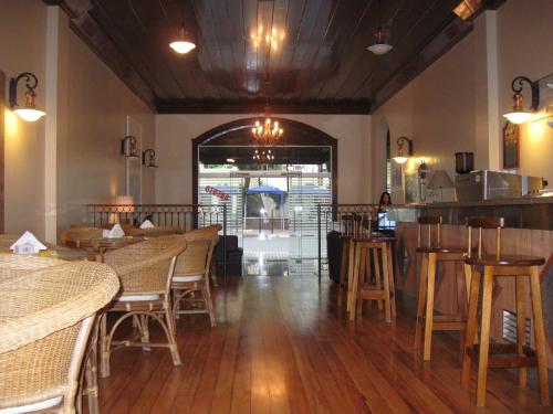 a restaurant with wooden tables and chairs and a bar at Hotel Praça da Matriz in Itapira