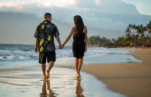 a man and a woman walking on the beach at Maui Coast Hotel in Kihei