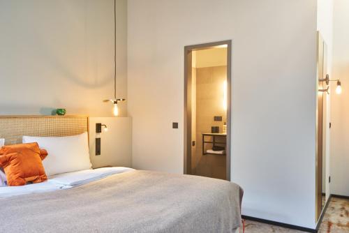 a bedroom with a large bed with an orange pillow at hood house in Hamburg