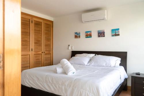 Un dormitorio con una cama blanca con toallas. en Aptos Alcazar Oviedo By HOUSY HOST, en Medellín