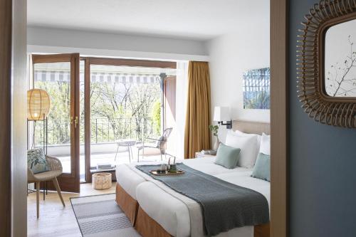 um quarto de hotel com uma cama e uma varanda em Castello del Sole Beach Resort&SPA em Ascona