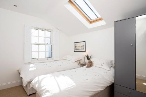 two beds in a white bedroom with a window at Finest Retreats - Walney Island Lighthouse in Rampside