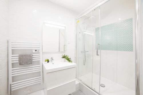 une salle de bain blanche avec un lavabo et une douche dans l'établissement MIRROR HOUSE - 130M2 - 3BR / 3BA Aircon Paris 2, à Paris