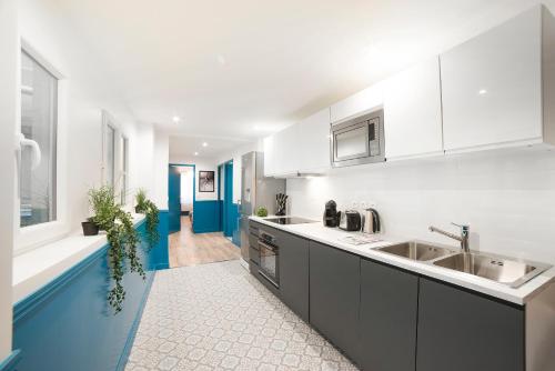 une cuisine avec des armoires blanches et un évier dans l'établissement MIRROR HOUSE - 130M2 - 3BR / 3BA Aircon Paris 2, à Paris
