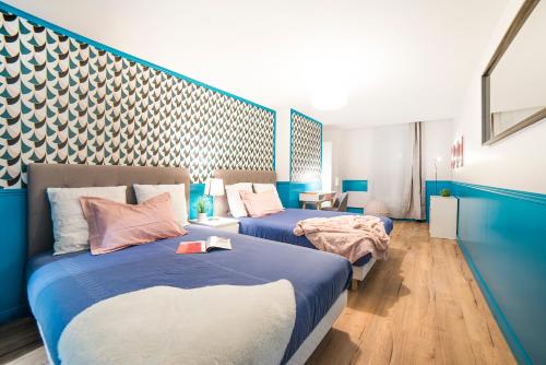 deux lits dans une chambre avec du bleu et du blanc dans l'établissement MIRROR HOUSE - 130M2 - 3BR / 3BA Aircon Paris 2, à Paris