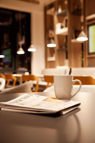 a cup of coffee sitting on a table with a newspaper at Holiday Inn Express Munich - Olympiapark by IHG in Munich