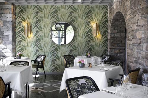 un restaurant avec des tables blanches et une fresque murale. dans l'établissement Castello del Sole Beach Resort&SPA, à Ascona