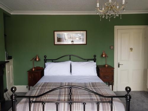 Un dormitorio con una cama con paredes verdes y una lámpara de araña. en Afallon Townhouse Gwynedd Room en Dolgellau