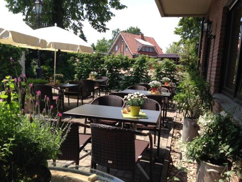 un patio al aire libre con mesas, sillas y flores en Hotel Wolfsjäger, en Herbern