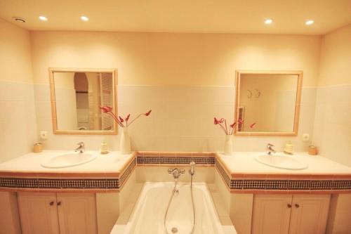 une salle de bain avec deux lavabos et deux miroirs dans l'établissement L Orangerie Spacieux appartement deluxe dans le centre historique, à Avignon