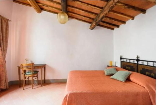 um quarto com uma cama laranja e uma mesa em Agriturismo le Bartaline em Pieve di Panzano