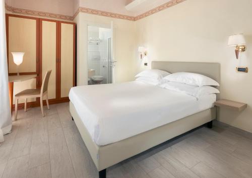 a bedroom with a large white bed and a desk at Hotel Bikini in Rimini