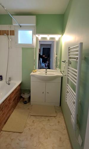 une salle de bain avec un lavabo, une baignoire et un miroir dans l'établissement De la détente dans ce coin de campagne., à Équemauville