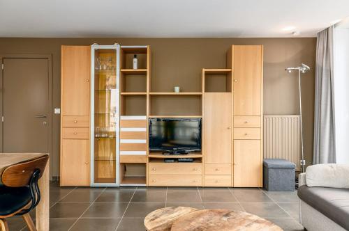 a living room with a entertainment center with a tv at Centre Leopold 204 in De Panne