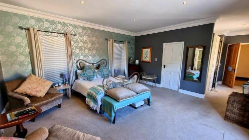 1 dormitorio con 1 cama y 1 silla en Sandmartins Private Secure Villa en Simondium