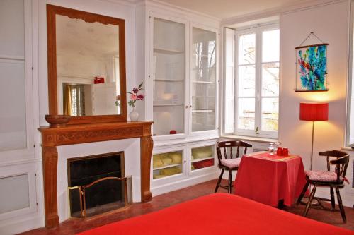 a room with a fireplace and a table with a red blanket at L'Ecrin du Serein in Sainte-Vertu