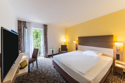 a hotel room with a large bed and a tv at Best Western Plus Hotel Koeln City in Cologne