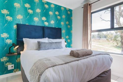 a bedroom with a large bed with a blue wall at Alimama Spaces: The Green Park Haven 2 in Johannesburg