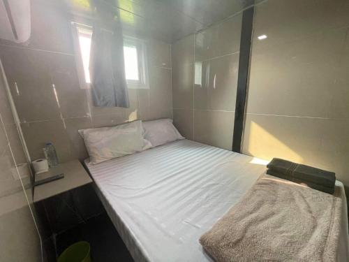 a small bed in a small room with a window at Charinsup Pinklao Hotel in Bang Kruai
