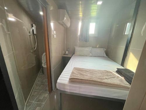 a small room with a bed and a shower at Charinsup Pinklao Hotel in Bang Kruai