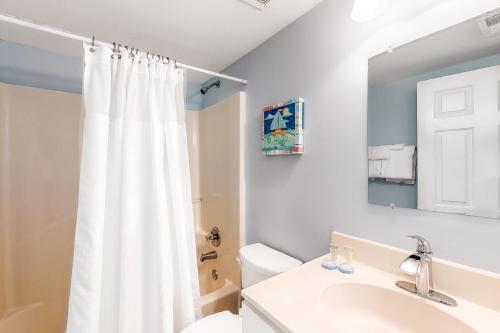 a bathroom with a white shower curtain and a sink at Tradewinds #1008 in Orange Beach