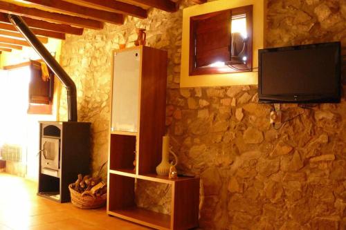 um quarto com uma parede de pedra, um frigorífico e uma televisão em Apartamentos Rurales La Fàbrica em Agost