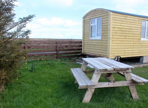 a picnic table in front of a tiny house at Hillside Camping Pods and Shepherd's Hut in Wick