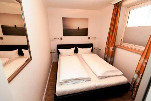 ein kleines Schlafzimmer mit einem Bett und einem Spiegel in der Unterkunft Ferienwohnung Dünenblick in Westerland